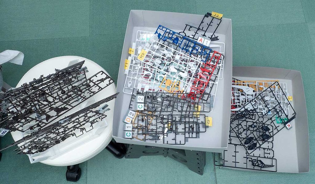 MGバルバトスルプスの作業中の机。箱や台にランナーを広げてタグで仕分けている